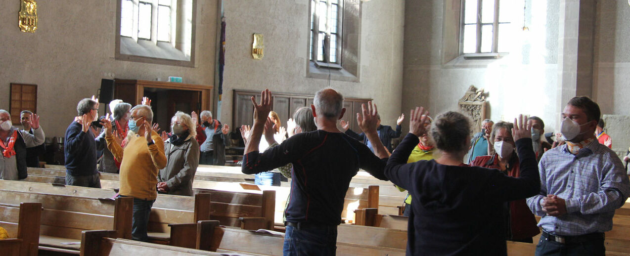 Im Gottesdienst spendeten sich die Menschen einen Friedensgruß, indem sie die Hände zum Himmeln reckten und sich gegenseitig Frieden wünschten. (Foto: Matthias Band)