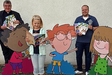 Monsignore Georg Austen, das Kommunionkind Marie Scholz und Julian Heese, Referent für Missionarische und diakonische Pastoral im Bonifatiuswerk, präsentieren die Sonderausgabe der bonkids zur Erstkommunion. (Foto: Sr. Theresita M. Müller)