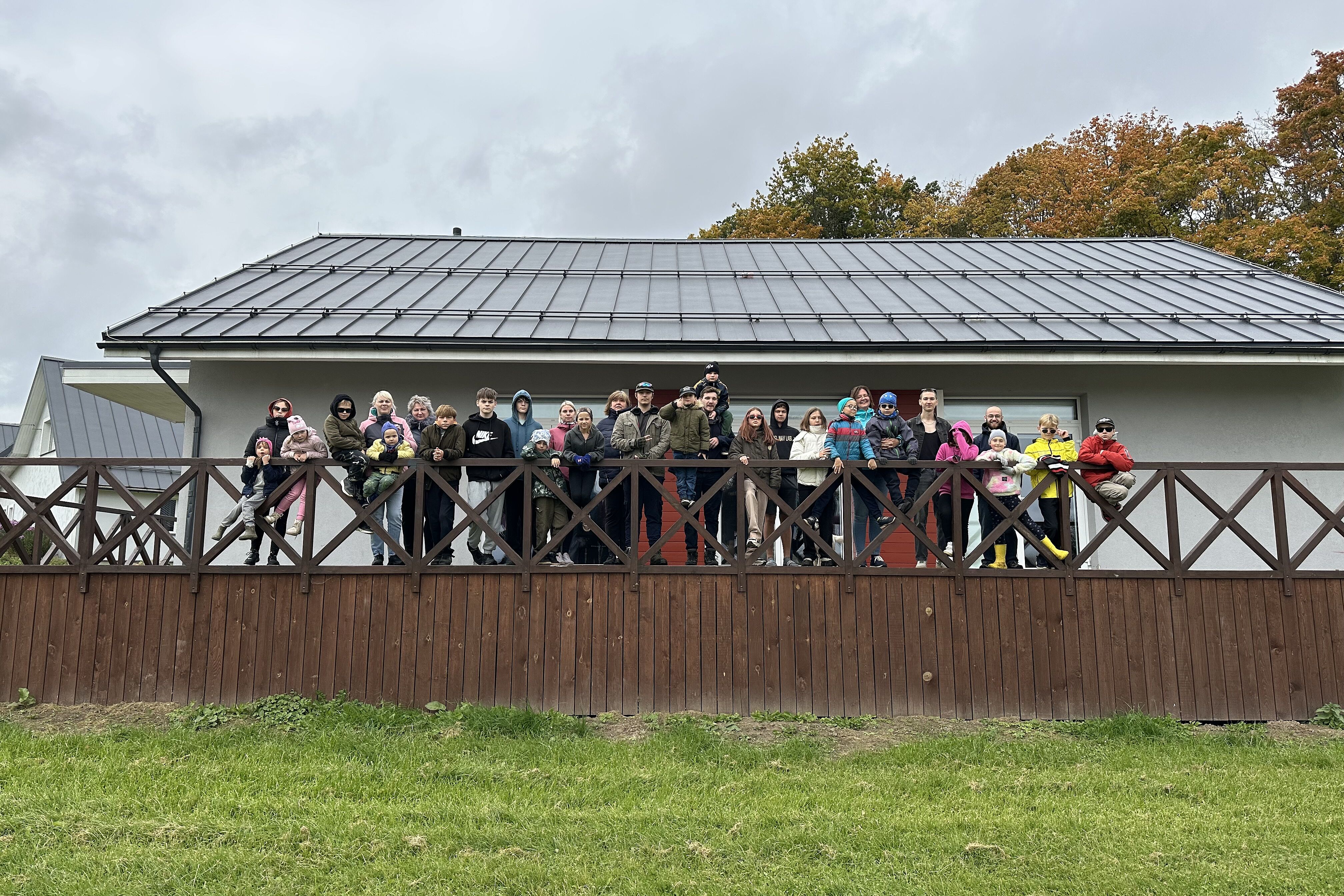 Kinder, Jugendliche und Erzieherinnen auf der Veranda eines Wohnhauses im Kinderdorf (Foto: Ieva Geidmane)