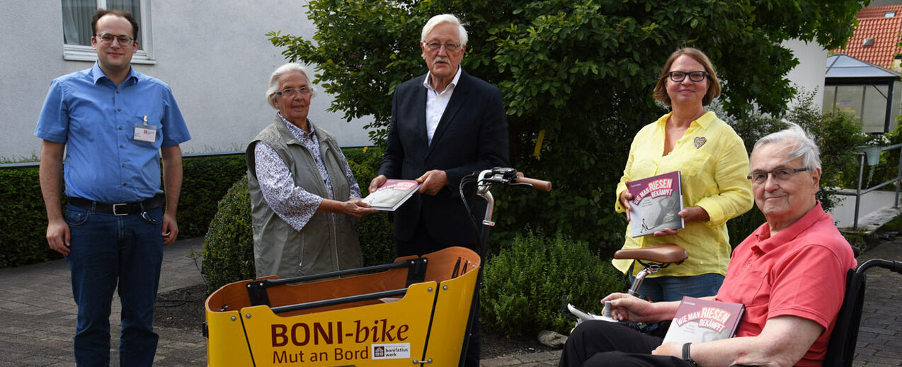 Freuen sich über die Mutmachbücher: Bewohnerin Ottilie Schmalzgrüber, Annette Wolff-Kropp, Leiterin Sozialer Dienst, und Bewohner Hermann Zeyen (v.l.) Der Bonifatiuswerk-Referent Daniel Born und der Präsident des Hilfswerkes, Heinz Paus, überreichen die Bücher (v.l.). (Foto: Theresa Meier)