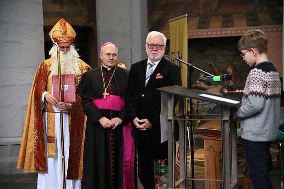 Ein Schüler trägt Bischof Nikolaus, Bischof Dieser und Bürgermeister Norbert Plum (v.l.) seine Forderungen gegen Kinderarbeit vor. (Foto: Theresa Meier)