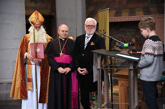 Ein Schüler trägt Bischof Nikolaus, Bischof Dieser und Bürgermeister Norbert Plum (v.l.) seine Forderungen gegen Kinderarbeit vor. (Foto: Theresa Meier)