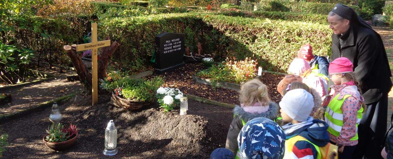 Schwester M. Victoria mit den Kindergartenkindern vor dem Grab des verstorbenen Pfarrer Bernhard Walter (Foto: C. Lehmann)