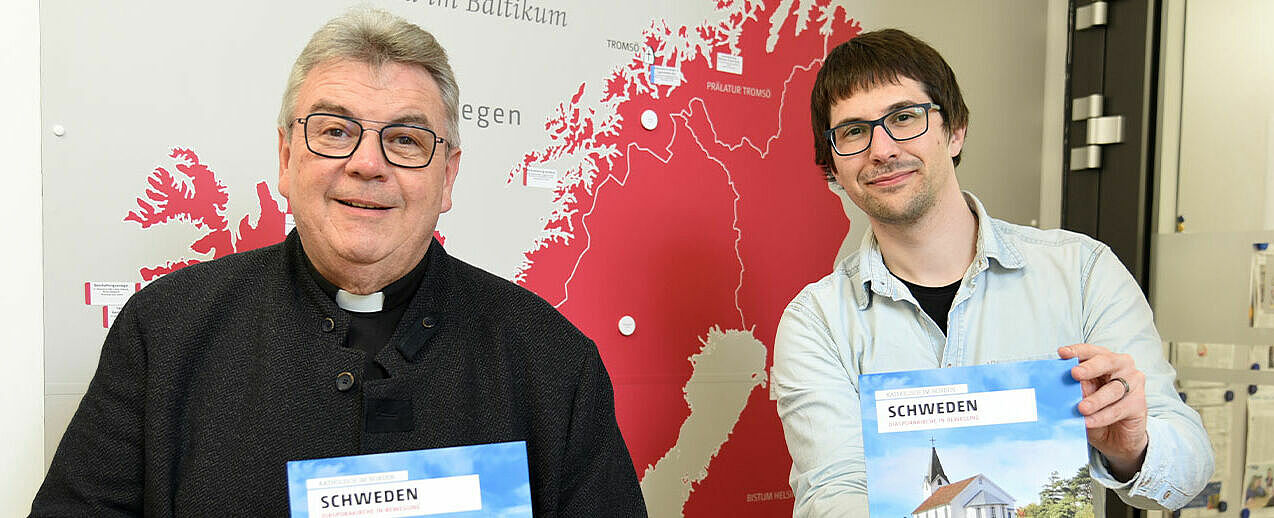 Monsignore Georg Austen, Generalsekretär des Bonifatiuswerkes, und Redakteur Simon Helmers (rechts) mit der Neuauflage 2Schweden. Diasporakirche in Bewegung2. (Foto: Theresa Meier/Bonifatiuswerk)