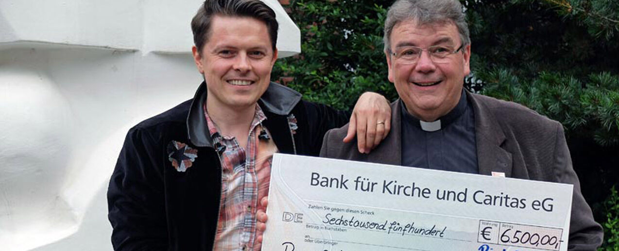 Michael Patrick Kelly und Monsignore Georg Austen bei der Scheckübergabe. Mit den 6.500 Euro unterstützt das Bonifatiuswerk die „Fazenda da Esperança“, ein Wohnprojekt für ehemalige Drogen- und Alkoholabhängige in Nauen in Brandenburg.