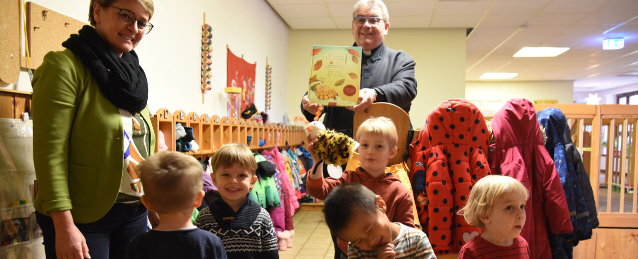 Msgr. Georg Austen, Generalsekretär des Bonifatiuswerkes, übergibt persönlich ein Hummel Bommel Buch an die Kinder der Kita St. Nikolaus in Erfurt und deren Leiterin Anja Köllner (Foto: Theresa Meier) 