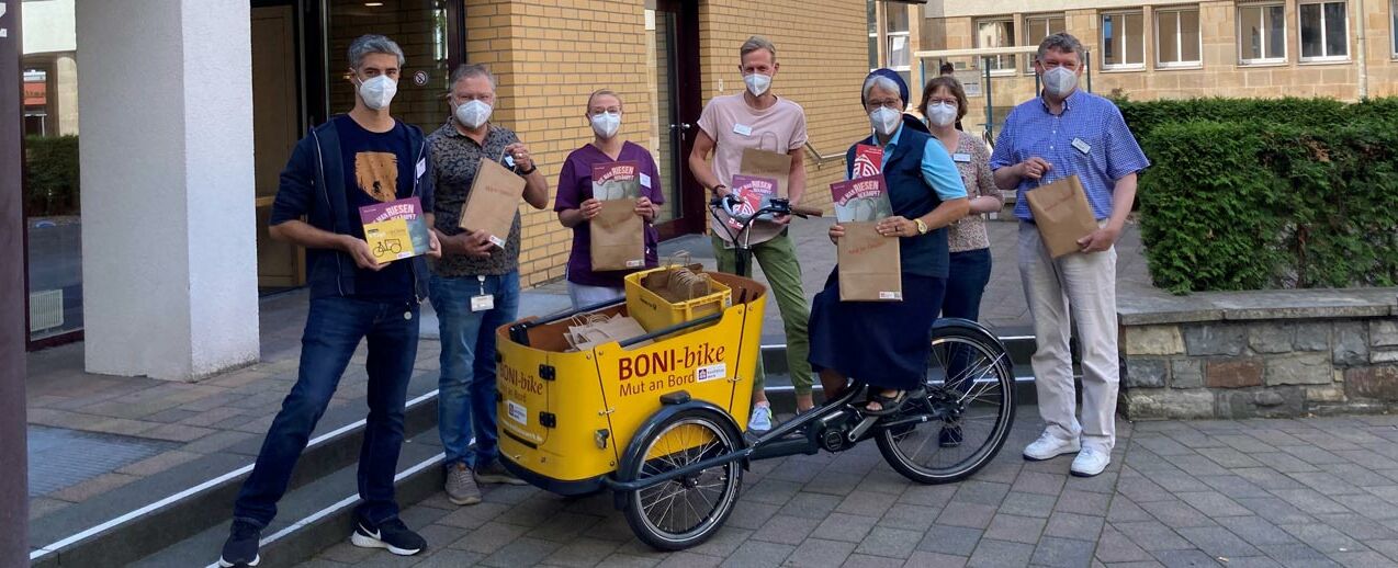 Christoph Pilz vom Bonifatiuswerk (l.) übergibt Mutmachbücher für Mitarbeiterinnen und Mitarbeiter des Krankenhaus St. Vinzenz in Paderborn. (Foto: Anke Füser)