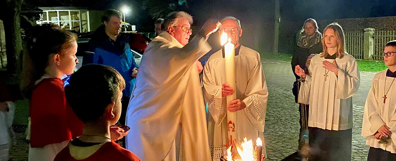 Bonifatiuswerk-Generalsekretär Monsignore Georg Austen entzündet die Osterkerze am Feuer vor der Pfarrkirche St. Marien in Fürstenberg. (Foto: Nicole Radtke)