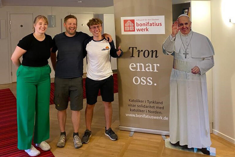 Marisa Grummich (Referentin des Bonifatiuswerkes), Sven Tönnies (Pastoralreferent im Bistum Münster) und Mirko Weih (Jugendvertreter aus dem Bistum Mainz) beim Gruppenfoto mit "Papst Franziskus" im Johannes Paulus II. Centrum in Stockholm. (Foto: Benjamin Rennert)