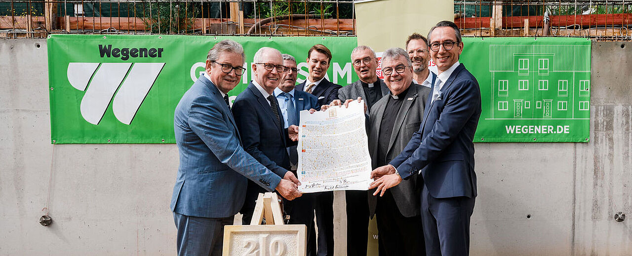 Dem Grundstein des Mehrgenerationenhauses wurde eine Urkunde beigelegt. Bürgermeister Michael Dreier, Bonifatiuswerk-Präsident Manfred Müller, Geschäftsführer Ingo Imenkämper, Christopher Gladen (Wegener Massivbau GmbH), Generalvikar Thomas Dornseifer, Monsignore Georg Austen, Architekt Carsten Scherhans und Jürgen Johannes Wegener (Wegener Massivbau GmbH, v.l.) brachten die Urkunde auf den Weg. Foto: André Heinermann
