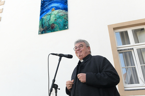 Monsignore Georg Austen steht vor dem Glasbild "Dach der Welt" und erklärt, warum das Bild am Bonifatiushaus aufgehängt worden ist. (Foto: Wilfried Hiegemann)