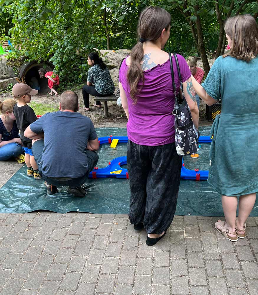 Während die Kinder an der Wasserbahn spielen, tauschen sich die Eltern im Gespräch aus. (Foto: Bettina Tönnesen-Hoffmann)