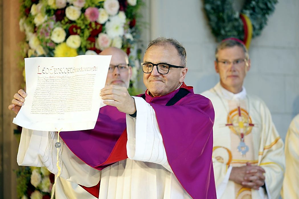 Die Ernennungsurkunde des Papstes, im Hintergrund rechts ist Bischof Dr. Heiner Wilmer zu sehen. (Foto: Bistum Münster)